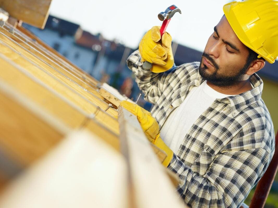 Roofer hammering fascia at a roof edge